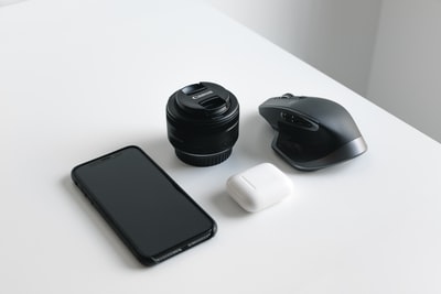 黑色智能手机，单反相机镜头。和无线电脑鼠标